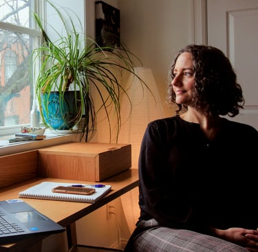 Angela Amirault, psychedelic therapist, sits in her office looking out the window