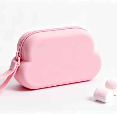 A pink, cloud-shaped silicone cosmetic pouch on a white background next to marshmallows.