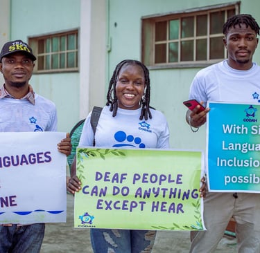 2 males and females holding a placard in recognition of sign language use and Deaf people.