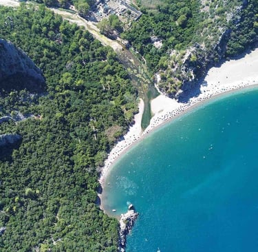 Olympos sahilinin ve antik kentin yeşillikler içindeki kıyısı, turkuaz deniz ve geniş kumsal havadan