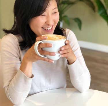 a woman is smiling and holding a cup of coffee