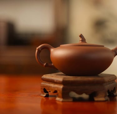 Dark brown, very flat teapot placed on a wooden stand