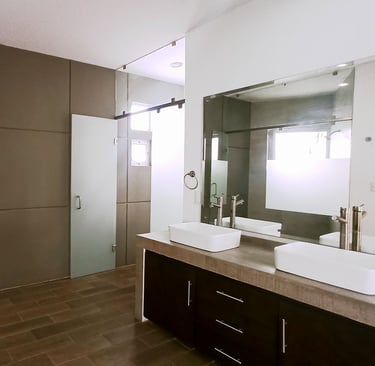 baño de recámara principal con espacios independientes y cancelería en cristal