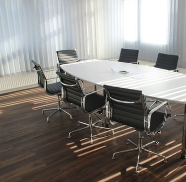 Modern meeting room with white conference table and black chairs 