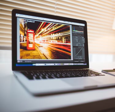 open laptop sitting on a white desk with the laptop screen showing sped up traffic and light