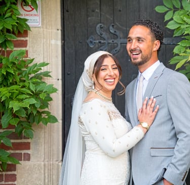 candid photo of bride and groom in front of stately home laughing and smiling