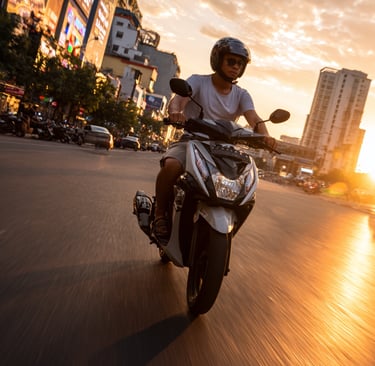 Young English teacher riding a scooter through Phnom Penh at sunset