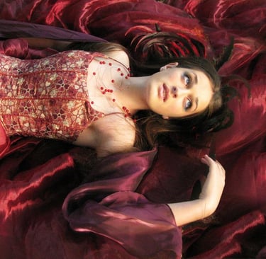 a woman in a red dress laying on a red blanket