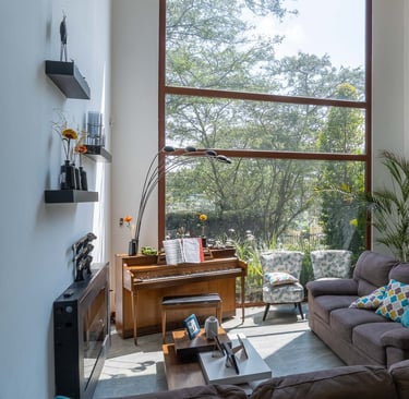 fotografía inmobiliaria quito ecuador tumbaco  gran sala de estar con muebles, piano y un gran ventanal con luz natural