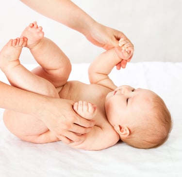 a baby is laying on a bed with a woman's hands