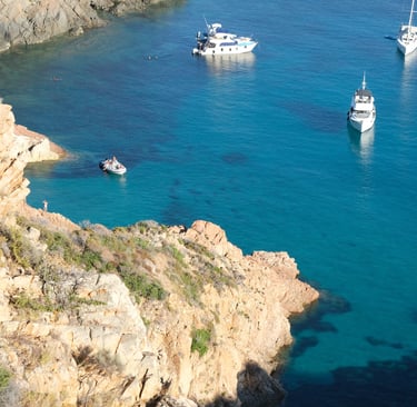 a group of boats in the water near a cliff