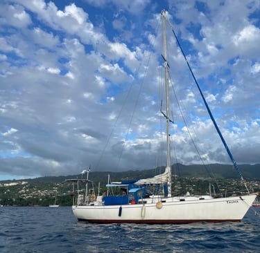 Sailboat Tauha behind the reef in crystal-clear waters near Tahiti, French Polynesia