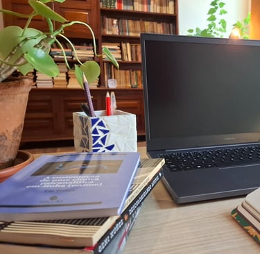 Mesa de trabalho com livros de autoras como Ana Suy, Gayle Rubin e Geni Núñez, ao lado do notebook u