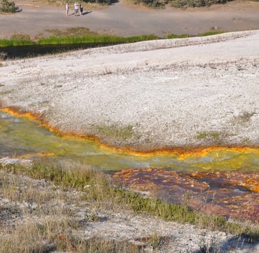 a stream of water with a person walking on it and geothermal activity