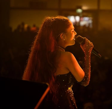 a woman in a black dress singing into a microphone