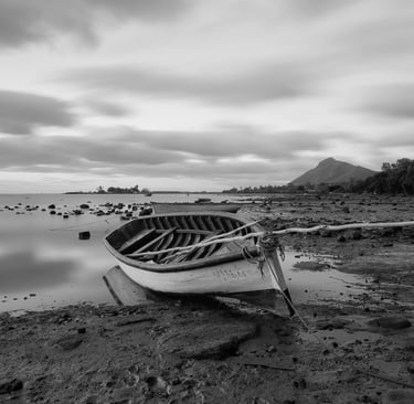 Long exposure shot of a wooden boat on a rocky shoreline at Petite Case Noyale in Mauritius