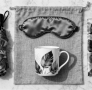 An elegant GWP lifestyle set including a compact umbrella, silk eye mask, and mug.