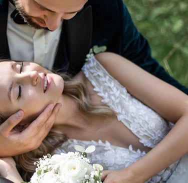 a bride and groom are sitting on the grass