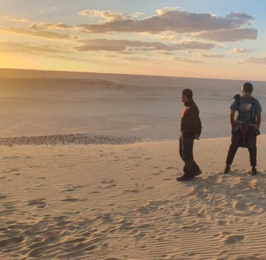 two people standing on a sand dune paragliding egypt
