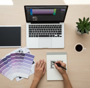 Scrivania di una graphic designer che lavora a una brand identity con palette colori, laptop e bozze