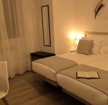 Habitación con camas gemelas en hotel Arias, Vigo, con espejo, ventana y lampara encendida