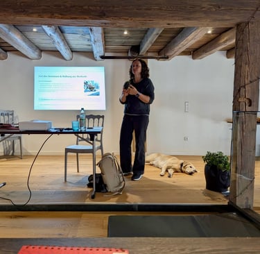 Svenja Stoll hält ein Seminar. Sie steht vor einer Präsentation und spricht zu den Teilnehmer:innen.