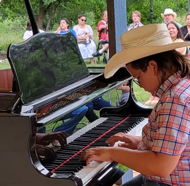 a young boy in a cowboy hat playing a piano