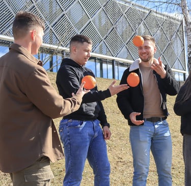 Jauni zmones lauke zaidzia su apelsinais