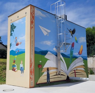 Fresque sur les façades d'un haut bâtiment. Un livre ouvert, des enfants jouent, un oiseau s'envole.