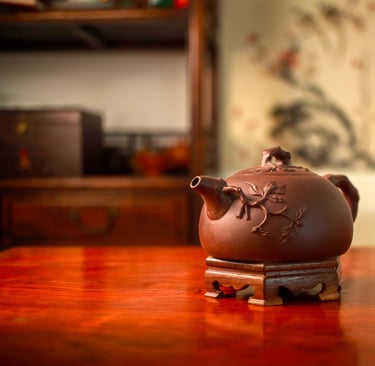 Teapot with an embossed design placed on a wooden stand