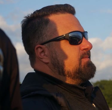a man with a beard and sunglasses on a sunny day