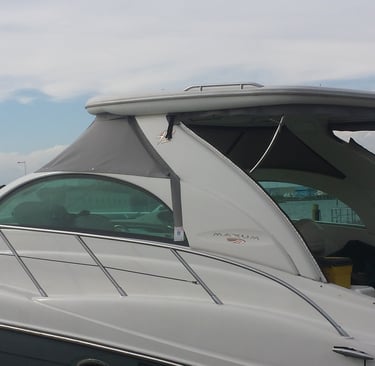 Side view of a white Maxum luxury motor yacht docked at a marina under a cloudy sky.
