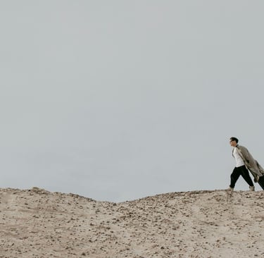 a man walking on a sandy hill with a suitcase