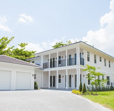a white luxury home with a large driveway shown and a two door garage