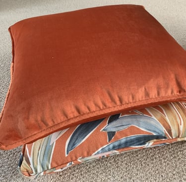 2 coordinated piped cushions with dominant colour in burnt orange