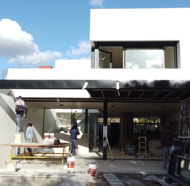 a man standing in front of a house with a large window