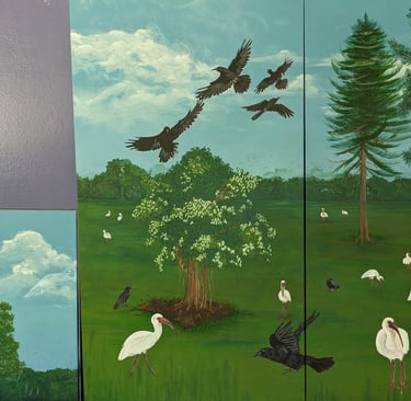 WIP photo of two of four canvas panels showcasing crow, trees, ibis, and a blue sky filled with clouds.