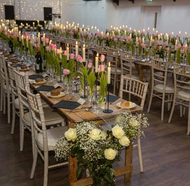 a long table with candles and flowers in a room