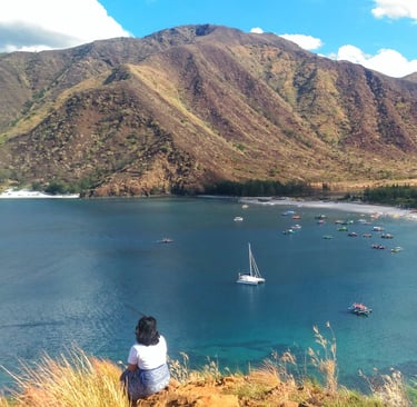 Stunning white sand beach in Zambales with a boat and mountain views, featured by Zam Realty.