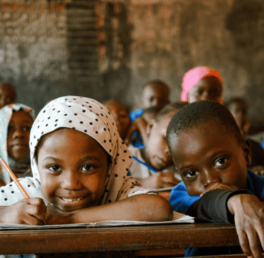 rootsandwings afrikanische schule unterstützen miembasabe schüler auch auf der sxhulbank schauen in die kamera