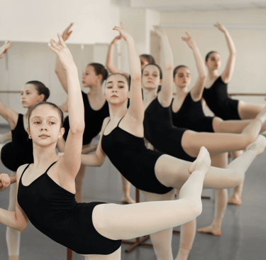 a group of young girls in black leotard in a dance class