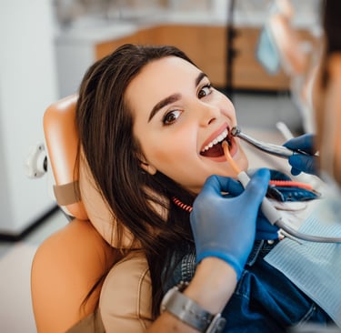 a woman is sitting in a chair and is having her teeth brushed