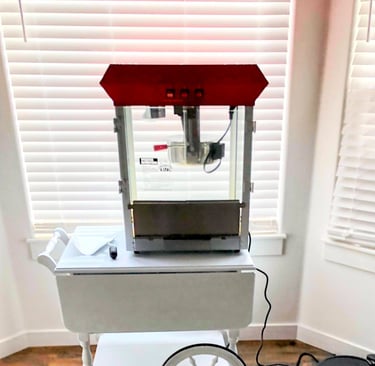a popcorn machine and popcorn scoop sitting on a white table