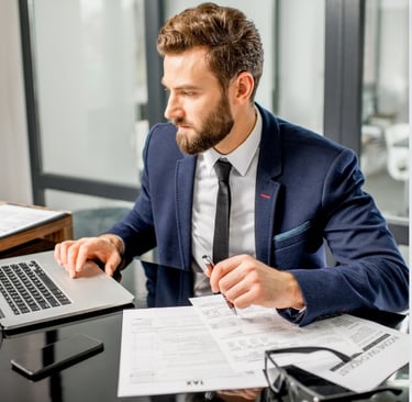 a man in a suit and tie is sitting at a desk with a laptop