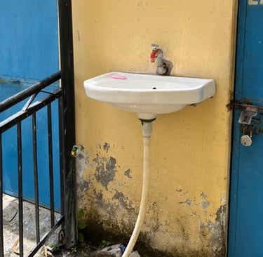 Small basin with single tap on yellow wall.