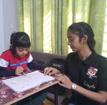 A Gharpadh tutor sitting on a couch with a child teaching