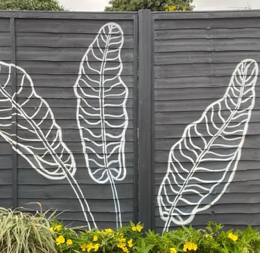 Modern graphic mural of three large tropical leaves on grey yard fence with flowers, by House of Lyr