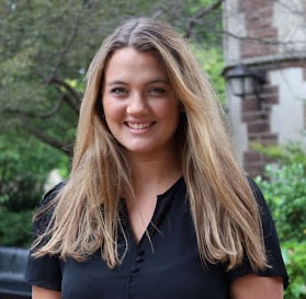 a headshot of a woman with long hair in front of a building