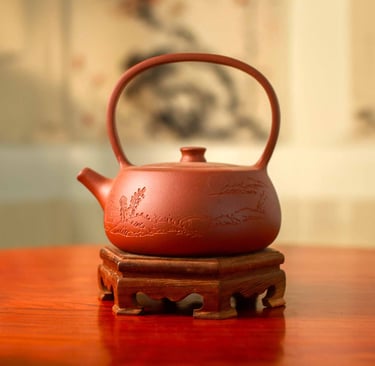 A brown teapot with carved artwork placed on a wooden stand