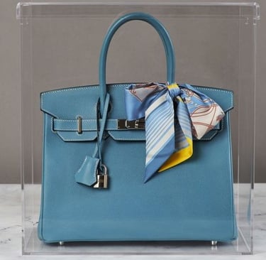 Blue luxury bag in a sleek acrylic display case.